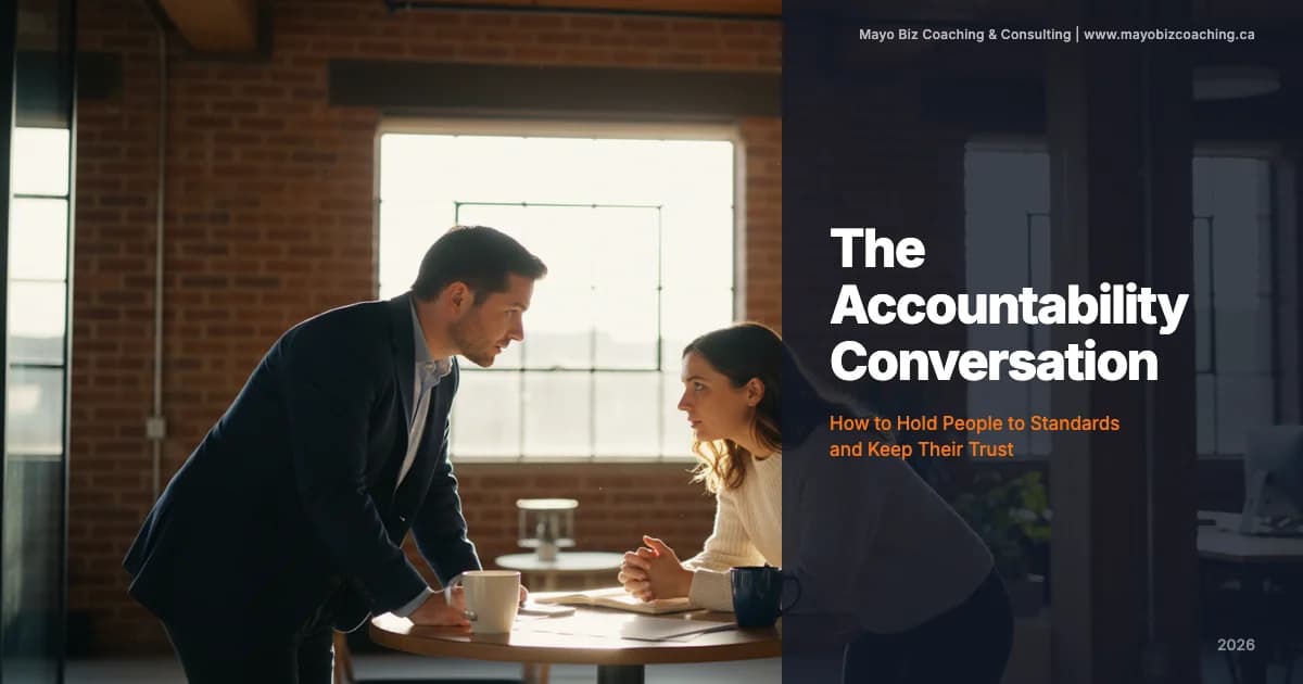 Leader having a direct accountability conversation with a team member in a warm office setting with natural light