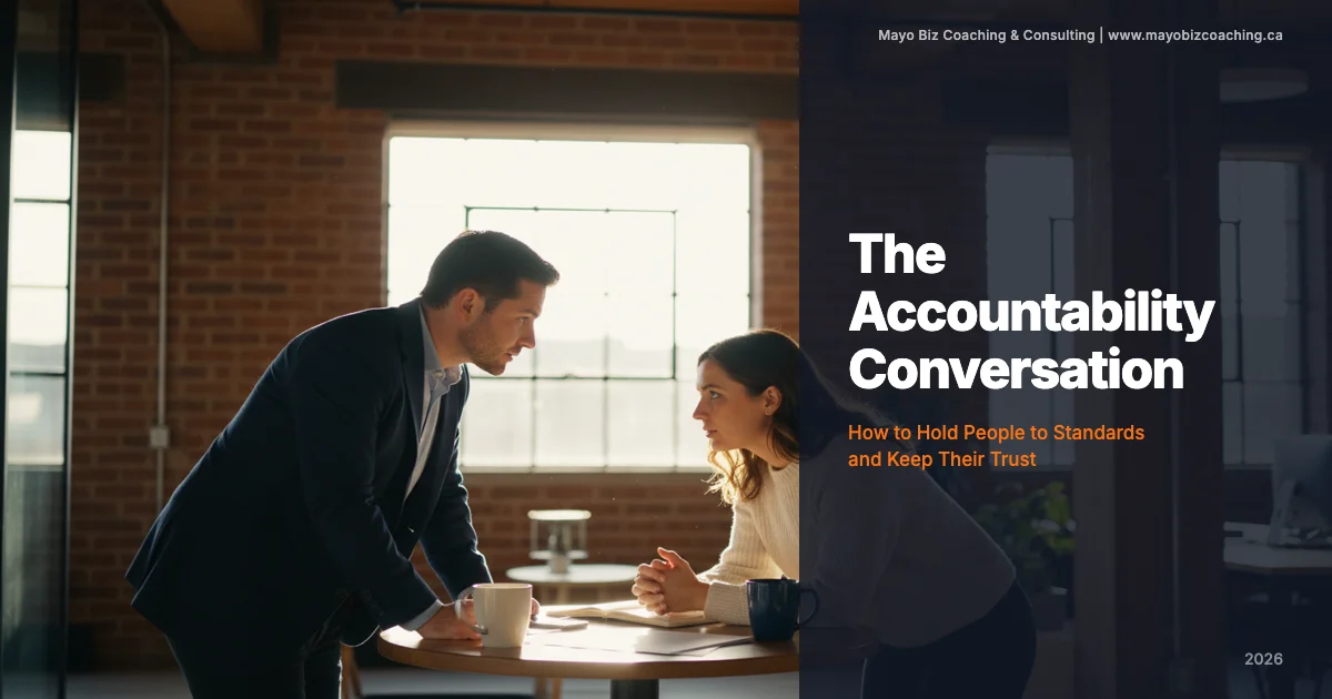 Leader having a direct accountability conversation with a team member in a warm office setting with natural light